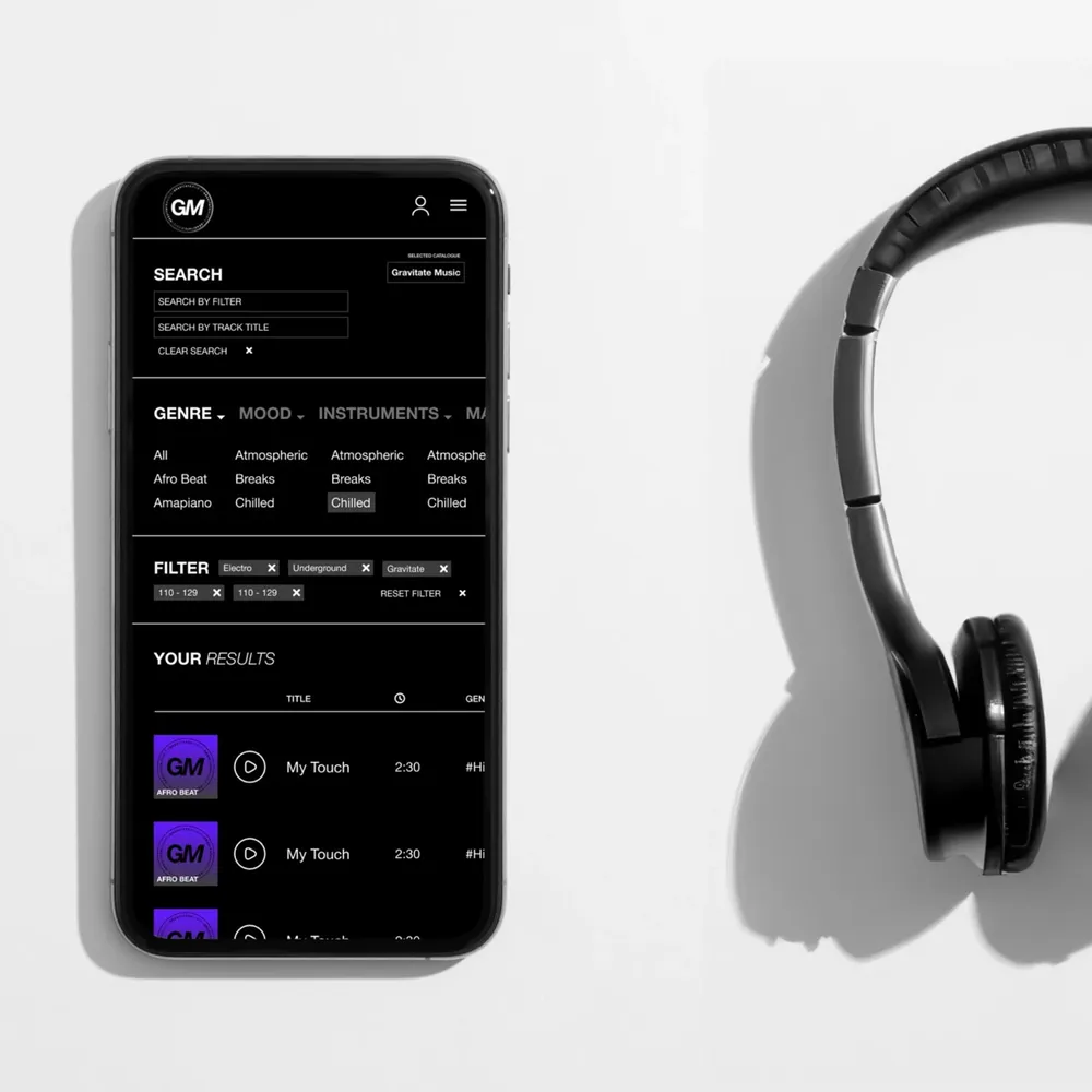 A smartphone showing search and filters lies next to a pair of headphones