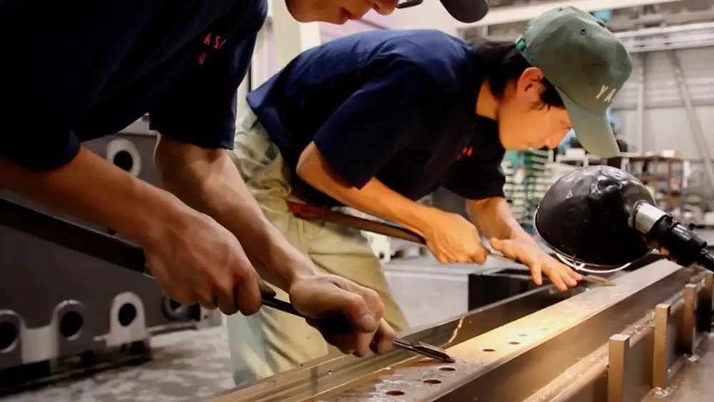 Two employees hand-scraping a guideway