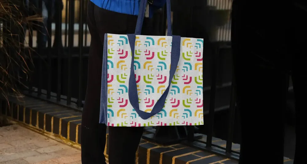 Tote bag with the bracket pattern in all four brand colors, carried on a staircase