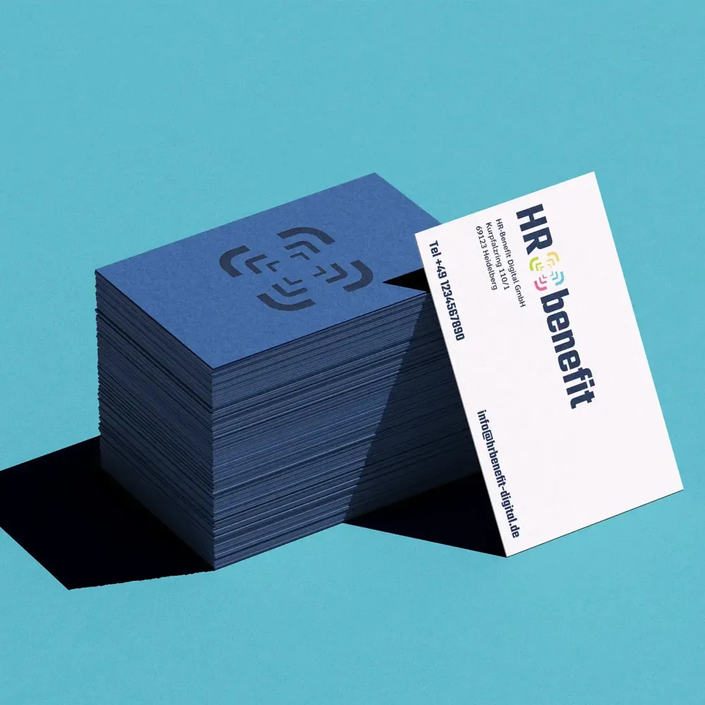 Stack of dark blue business cards with an embossed symbol, a white card with contact details in front of it