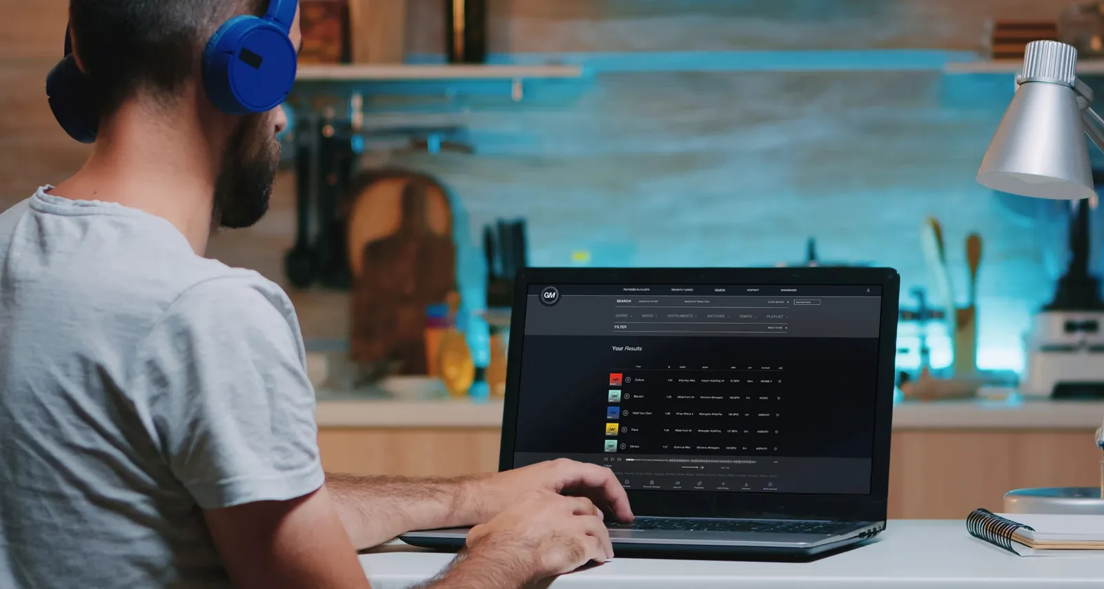 A producer with headphones at a laptop, the list of results on screen