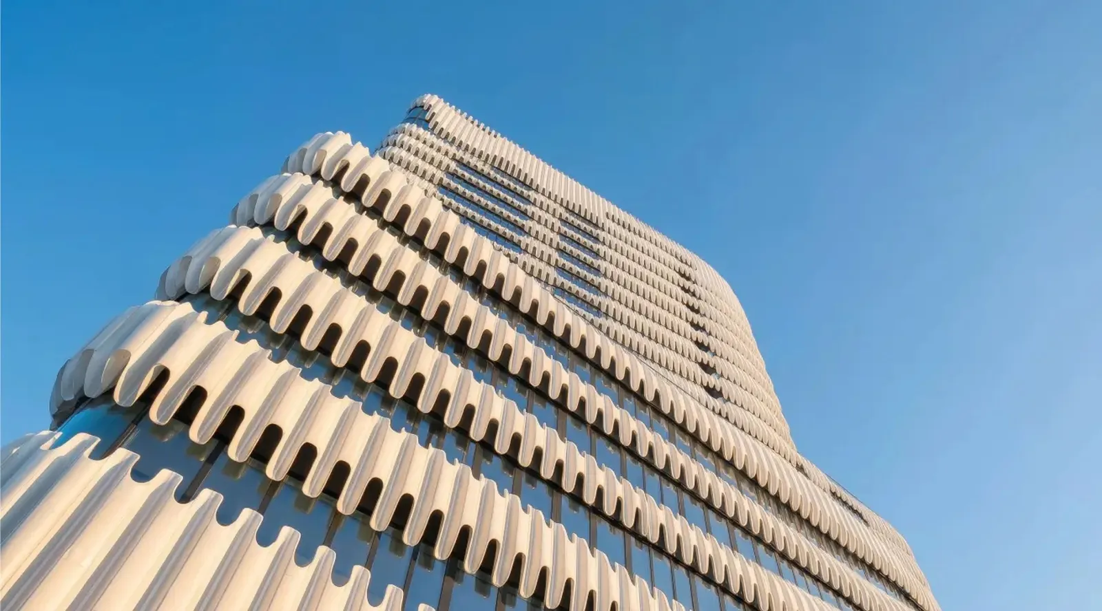 The undulating concrete facade of the RKM 740 office building in Düsseldorf-Heerdt against a blue sky