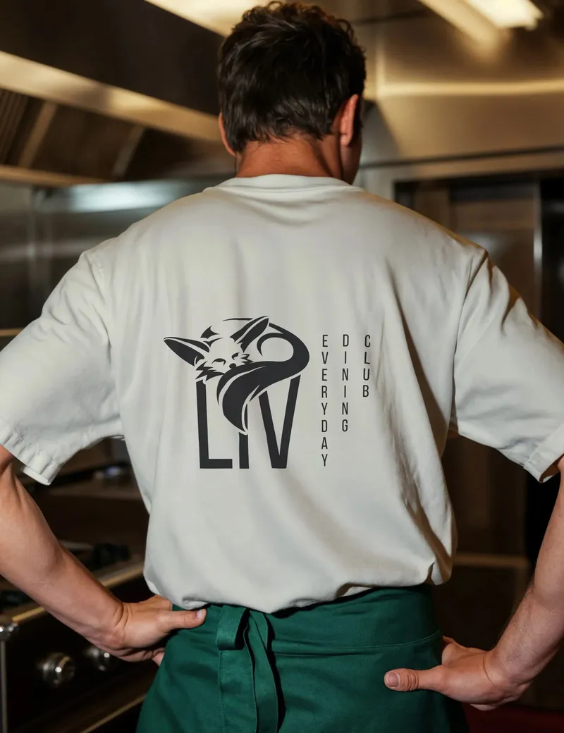 Kitchen staff seen from behind in a light T-shirt with the Liv logo on the back