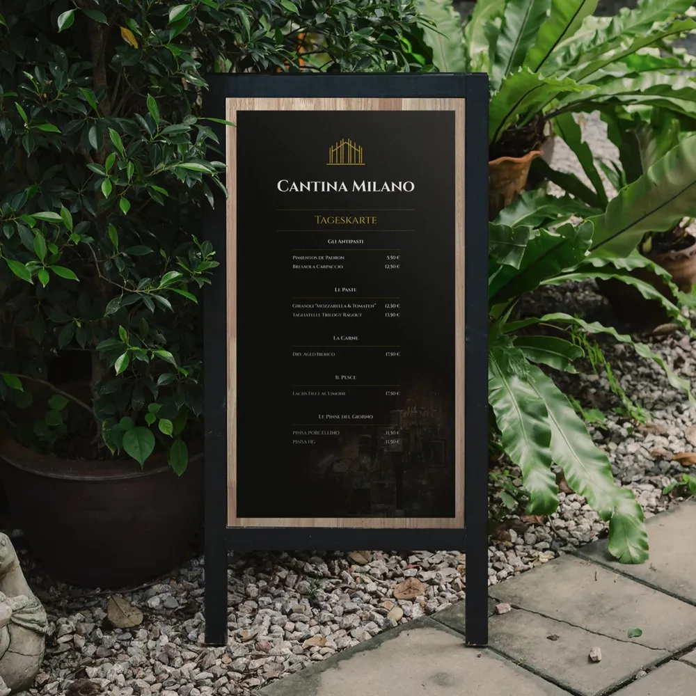 A pavement sign with the daily menu in front of the planted entrance side of the restaurant