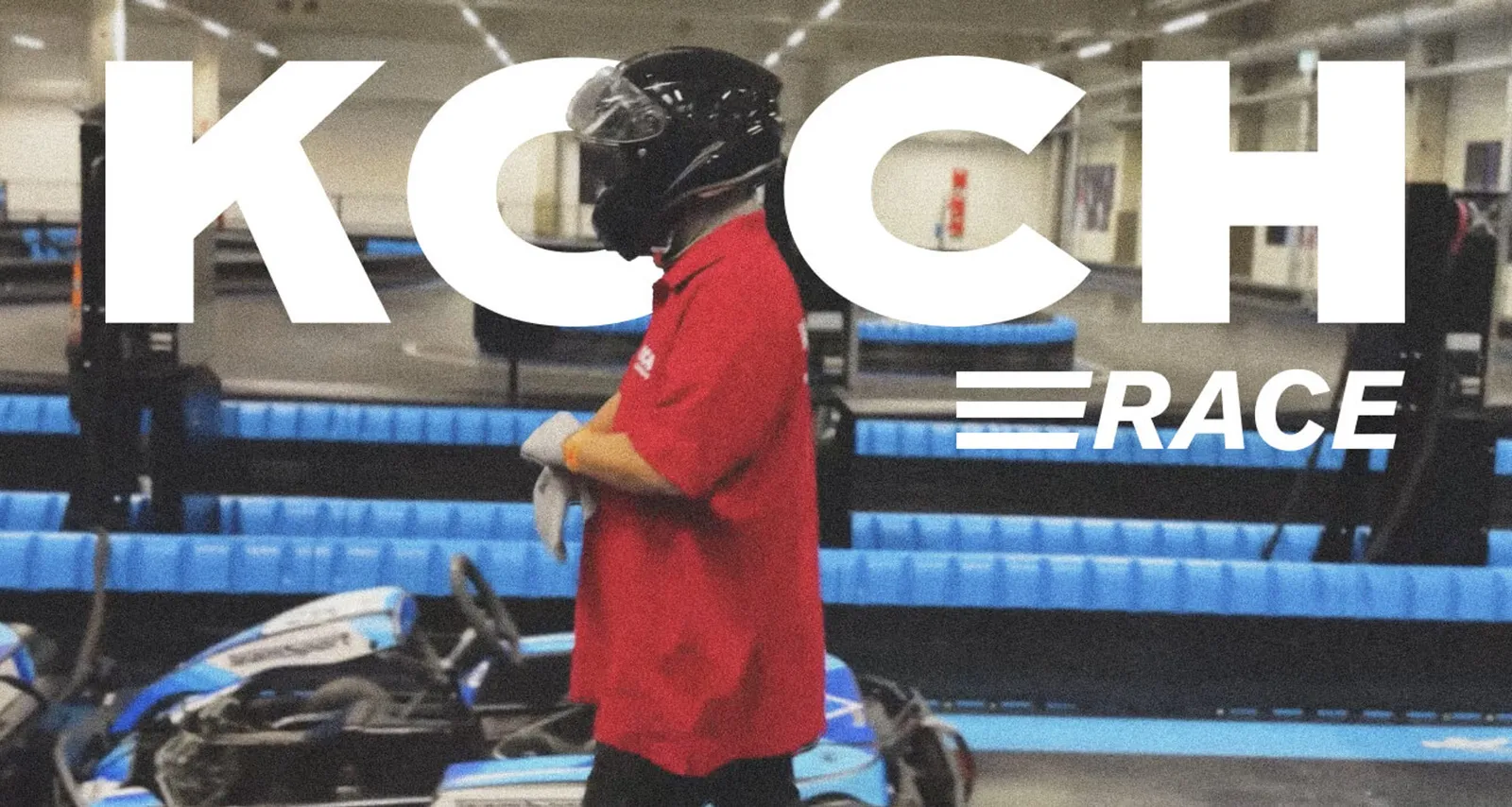 A driver in a red Koch polo shirt with a helmet at the kart track, with the “Koch Race” lettering above